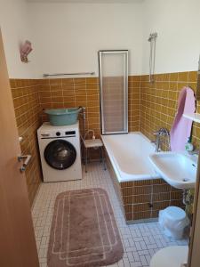a bathroom with a tub and a washing machine and a sink at Ferienhaus Seifert in Bischofsheim an der Rhön