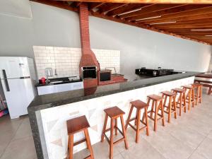 uma cozinha com um bar com bancos e um fogão em Recanto das Palmeiras - área de lazer em São Carlos em São Carlos