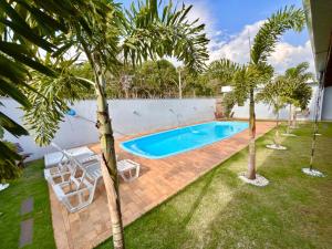 an image of a swimming pool in a yard with palm trees at Recanto das Palmeiras - área de lazer em São Carlos in São Carlos