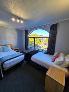 a hotel room with two beds and a window at Hacienda Motor Lodge in Palmerston North
