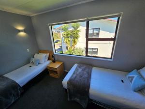 um quarto de hotel com duas camas e uma grande janela em Hacienda Motor Lodge em Palmerston North