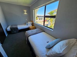 a hotel room with two beds and a large window at Hacienda Motor Lodge in Palmerston North