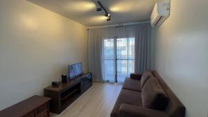 a living room with a couch and a television at Flat Saint Paul Jardim Paulista Magnifico! in Sao Paulo