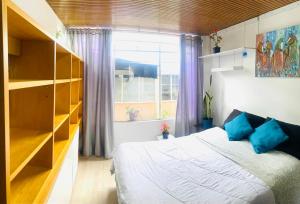 Un dormitorio con una cama con almohadas azules y una ventana en Hostel Usaquen Bogota, en Bogotá