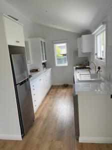 a kitchen with white cabinets and a stainless steel refrigerator at Character 1920s 3 bedroom bungalow in Cambridge