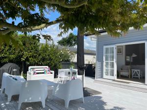 a patio with white chairs and a table and a house at Character 1920s 3 bedroom bungalow in Cambridge