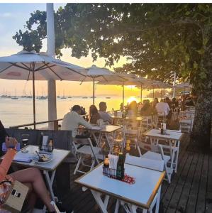 a group of people sitting at tables at a restaurant at Cabana com banheira de Hidro e vista para o mar, privativa e tranquila localização excelente in Florianópolis
