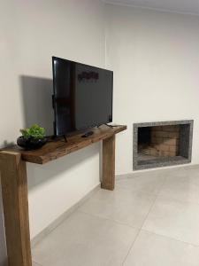 Une télévision à écran plat est installée au-dessus d'une table en bois. dans l'établissement CASA DA FONTE, à Bento Gonçalves