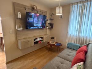 een woonkamer met een bank en een flatscreen-tv bij Acogedor apartamento centrico, tranquilo con piscina in Lima