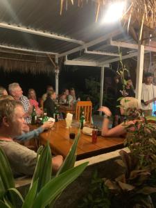 un grupo de personas sentadas alrededor de una mesa de madera en Dragonfly Senaru Lodge en Senaru
