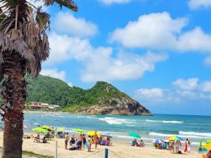 eine Gruppe von Menschen mit Sonnenschirmen an einem Strand in der Unterkunft Apartamento na Praia da Enseada, 100 mt praia in São Francisco do Sul