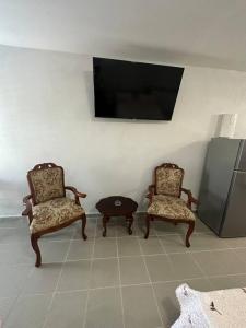 twee stoelen en een tafel in een kamer met een tv bij OceanView 2 in Guayama