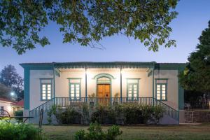 une grande maison blanche avec une terrasse couverte à l'avant de l'établissement la nuit dans l'établissement Limoeiro da Concórdia Hotel Fazenda de Charme, à Itu