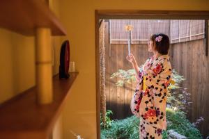 a woman in a kimono holding an umbrella at 京町　朱雀 in Kyoto