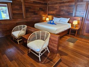 a bedroom with a bed and two chairs and a table at Andau Resort Raja Ampat in Tapokreng