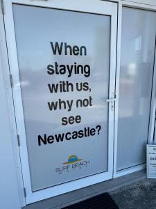 Surf Beach Motel Newcastle في نيوكاسل: علامة على باب يقول عند البقاء معنا لماذا لا نرى نشرة الأخبار