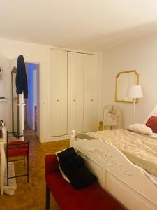 ein Schlafzimmer mit einem weißen Bett und einem roten Stuhl in der Unterkunft Logement unique et chic PARIS 15 min champs Élysée in Rueil-Malmaison