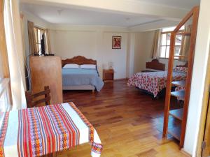 a bedroom with two beds and a wooden floor at Casa Saywa in Urubamba