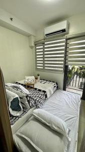 Cette chambre comprend deux lits et une fenêtre avec des stores. dans l'établissement Mall of Asia Shore 2 Condo, à Manille