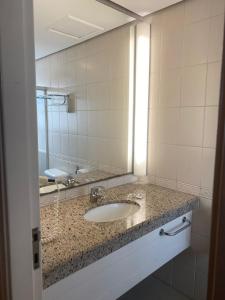 een badkamer met een wastafel en een grote spiegel bij Guarulhos Flats Services in Guarulhos