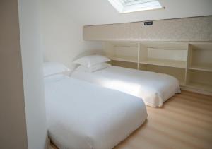 two white beds in a room with a window at Tingjian Lingyin Alanruo Design Homestay in Hangzhou