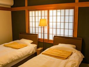 dwa łóżka w pokoju z oknem w obiekcie 1組限定　1棟貸切 「おとまり忠左衛門」　 グループや3世代旅行に最適　　　　 w mieście Ikeda