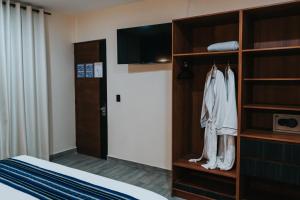 オアハカにあるHotel Casa Pugaのベッドルーム(クローゼット、ベッド、テレビ付)