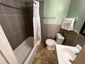 een badkamer met een bad, een toilet en een wastafel bij Town & Country Motel in Sioux City