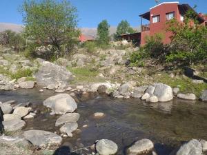 a river with rocks in front of a house at PORTAL DE LA OVEJERIA in Tafí del Valle +11 photos