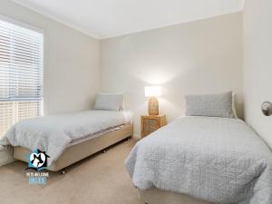 维克多港Light Filled Modern & Stylish 3BR Holiday Home的有两张床和一扇窗户的卧室