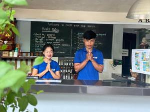 a man and a woman standing behind a counter praying at Siem Reap Pub Hostel in Siem Reap