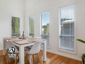 维克多港Light Filled Modern & Stylish 3BR Holiday Home的一间有桌椅和窗户的餐厅
