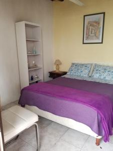 a bedroom with a purple bed and a chair at La Casa de Teresa in Colonia del Sacramento