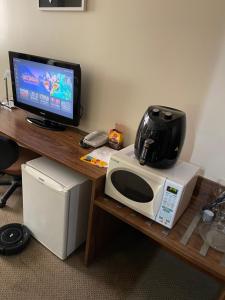 a microwave sitting on a table with a television on it at PROMOÇÃO EXECUTIVA COM BANHEIRA E FLATS SEM BANHEIRA- Melhor Hotel De Taguatinga in Taguatinga