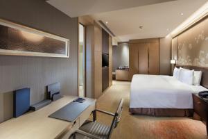 Habitación de hotel con cama y escritorio con ordenador en Hilton Yantai en Yantai
