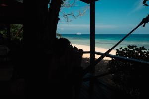 eine Person auf einer Veranda mit Blick auf den Strand in der Unterkunft Swiss Cottage Tioman in Tioman Island