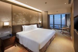 a large white bed in a room with a large window at Hilton Yantai in Yantai