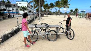a man and a boy standing next to a bike on the beach at La Casa de Joel in Puerto Villamil