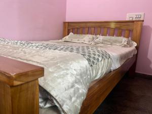 a bed in a room with a wooden bed frame at Spacious Queen Bed Suite 6km to Palace, Free Wi-Fi, Books, Toys, Smart TV in Mysore