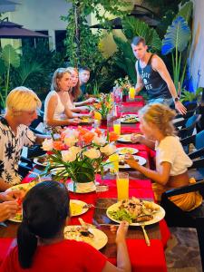 a group of people sitting at a table eating food at Ramzu Villa Thoddoo in Thoddoo
