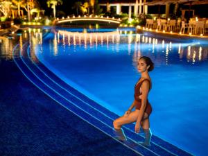 une femme dans une piscine la nuit dans l'établissement Oriental Hotel Okinawa Resort & Spa, à Nago