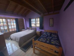 1 dormitorio con paredes de color púrpura, 1 cama y ventanas en El Peregrino, en Cota