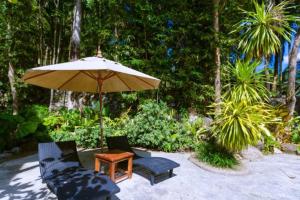 un patio avec deux chaises, une table et un parasol dans l'établissement Classic Thai style Cozy Villa fancy pool+garden, à Patong Beach