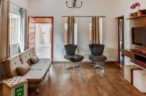 uma sala de estar com um sofá e duas cadeiras em CASA CHARME DO CERRADO em Pirenópolis