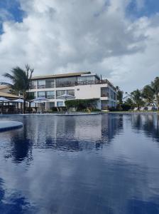 a large building with a swimming pool in front of it at Apartamento no Paraíso dos Corais in Camaçari