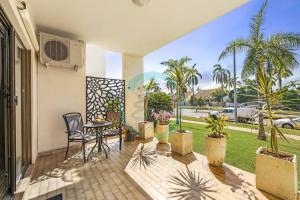 a patio with a table and chairs and palm trees at Zen by the Coast: 2-BR Cozy Retreat Near Uni/Shops in Casuarina