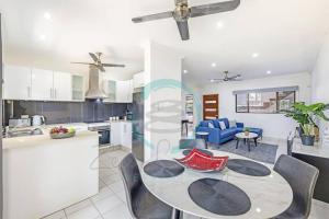a kitchen and living room with a table and chairs at Zen by the Coast: 2-BR Cozy Retreat Near Uni/Shops in Casuarina