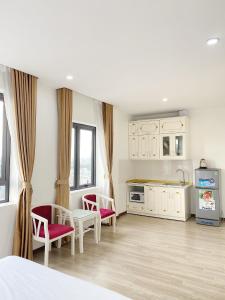 a bedroom with a bed and two chairs and a kitchen at Grand Hill Hotel & Apartment in Hai Phong