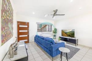 a living room with a blue couch and a tv at Zen by the Coast: 2-BR Cozy Retreat Near Uni/Shops in Casuarina