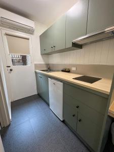 a kitchen with white cabinets and a white refrigerator at Summerhill Motor Inn in Merimbula